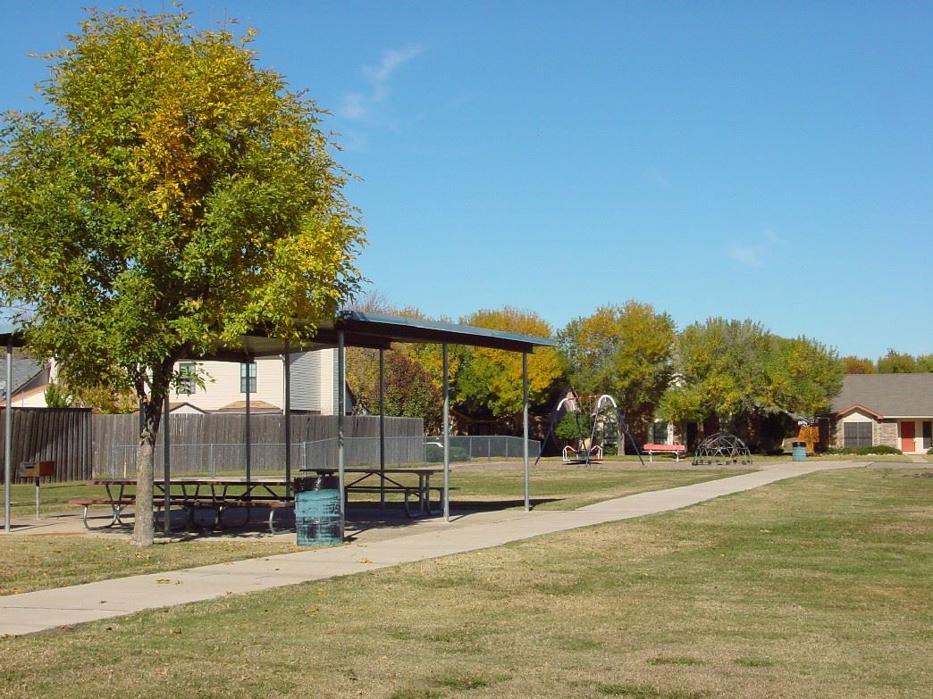 Park with a covered picnic area, playground equipment and trees